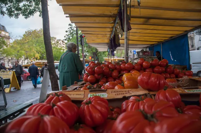 Étal de tomates et de poivrons sous un auvent jaune
