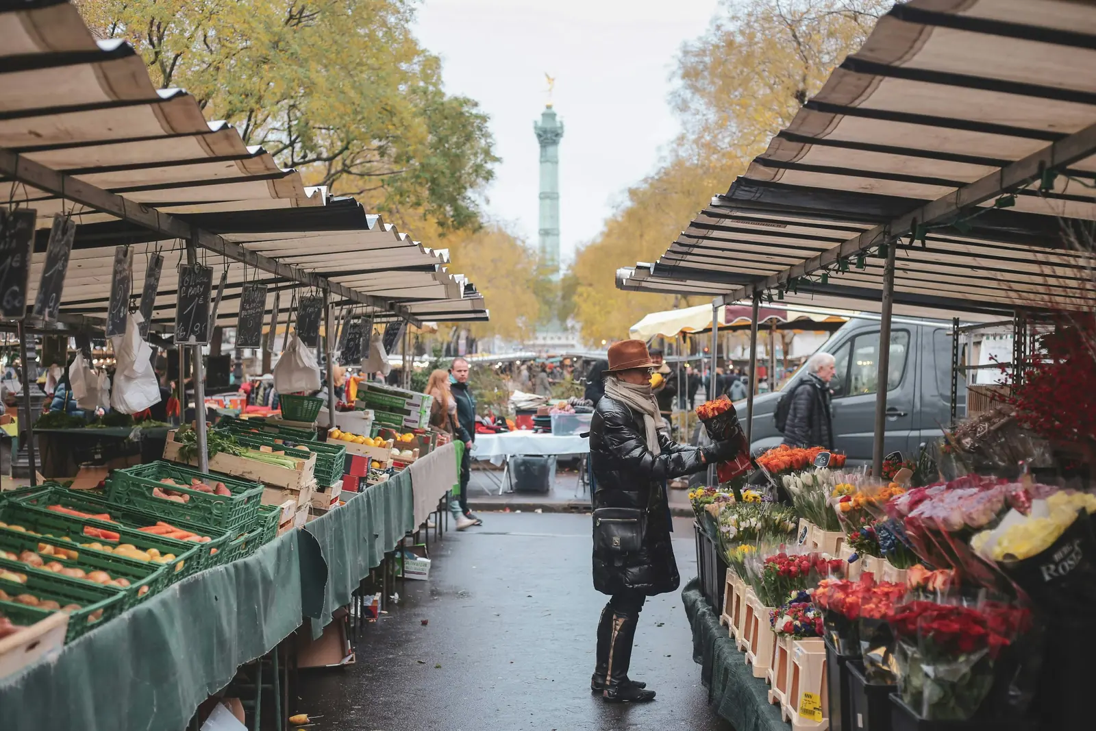 Allée d’un marché de plein vent parisien, étals sous auvents rayés